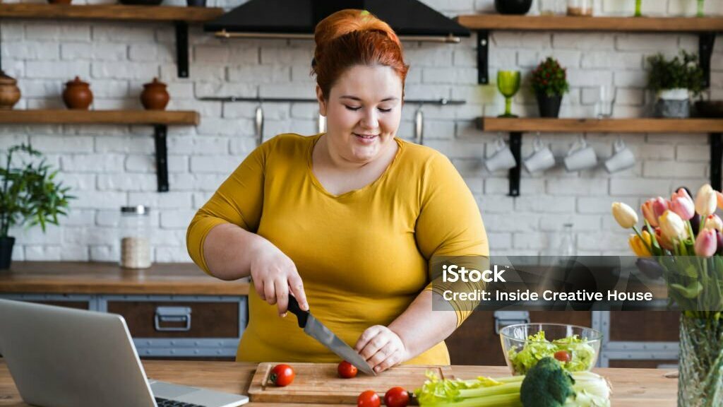 Personne en surpoids faisant la cuisine avec des légumes